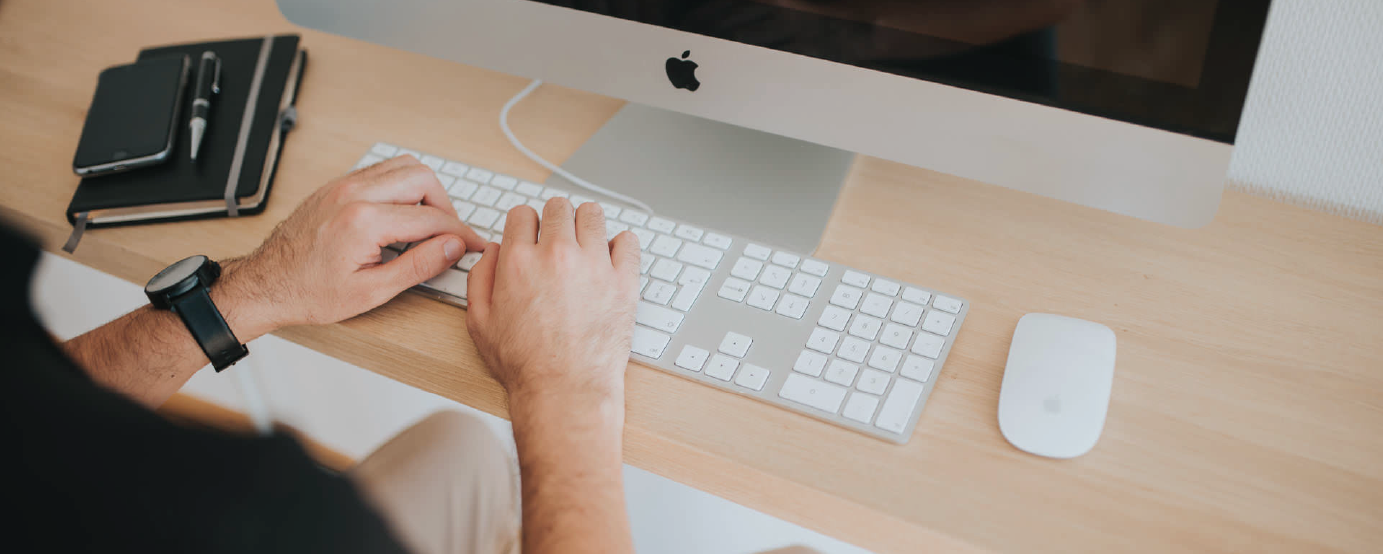 person, not visible, sitting at computer presses keyboard keys