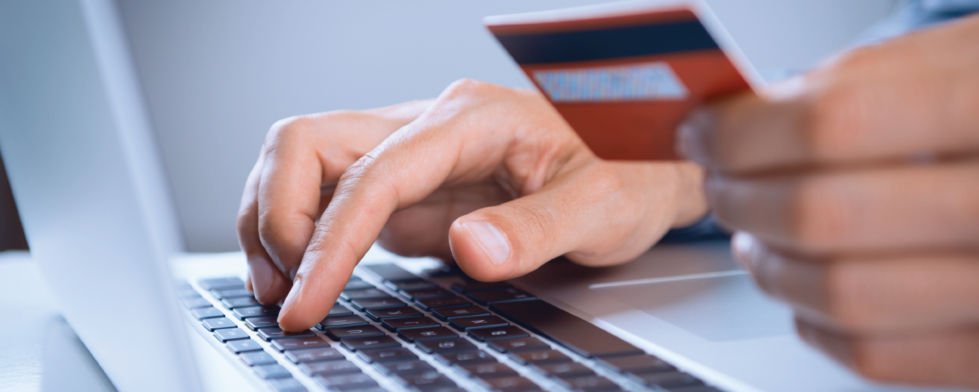 person typing in credit card number on laptop