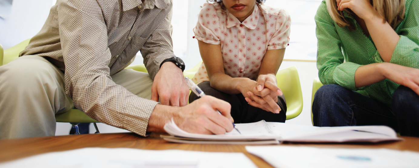 Three people reviewing items in notebook