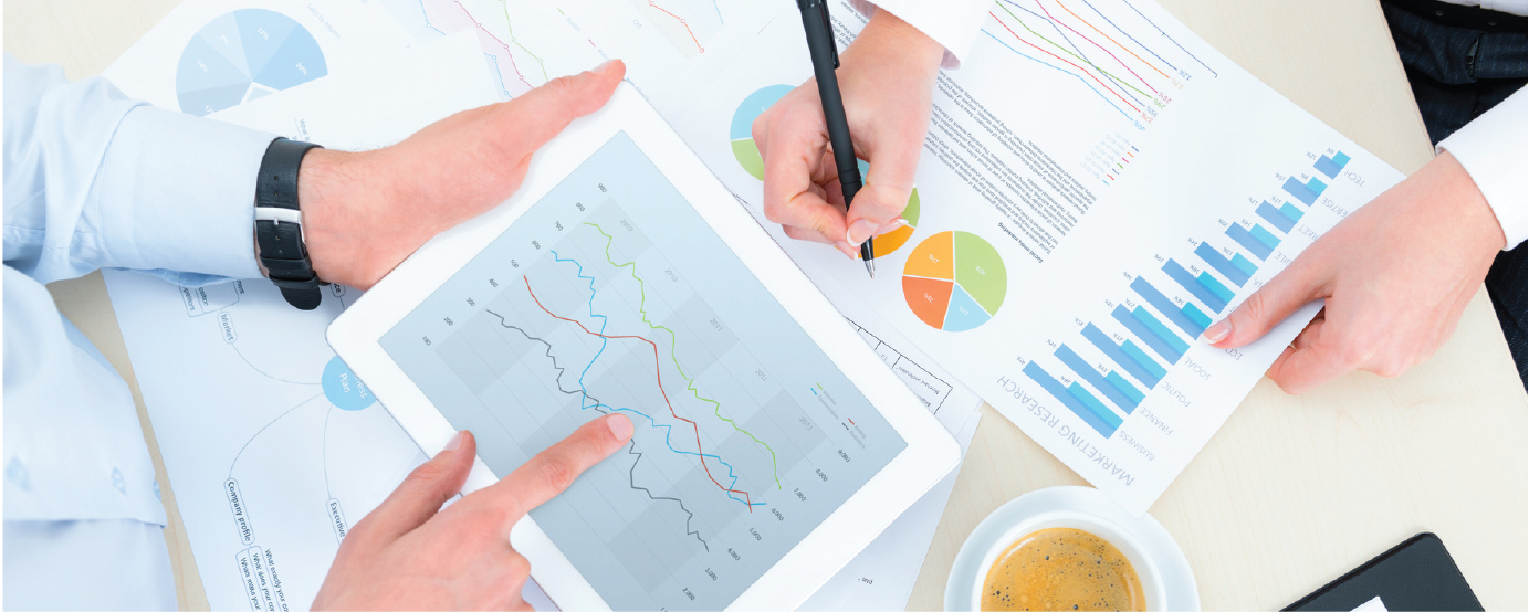 Two people not visible looking at graphs on ipad and paper