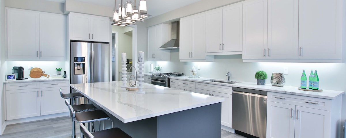 Photo of newly remodeled kitchen with white cabinets and blue island