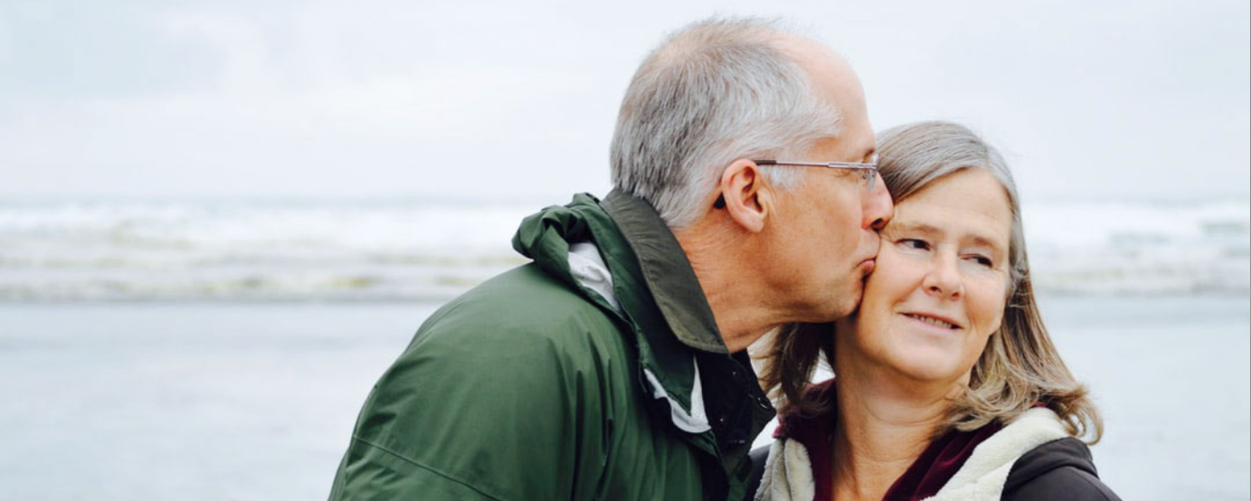Photo of empty nest age couple with blurred lake in background