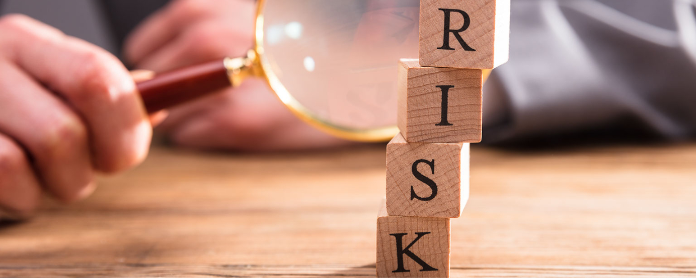 Close up of little blocks spelling out RISK blurred hands holding a magnifying glass close to blocks