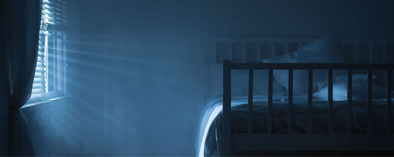 Photo of wooden bed and pillows light barely shining thru closed blinds