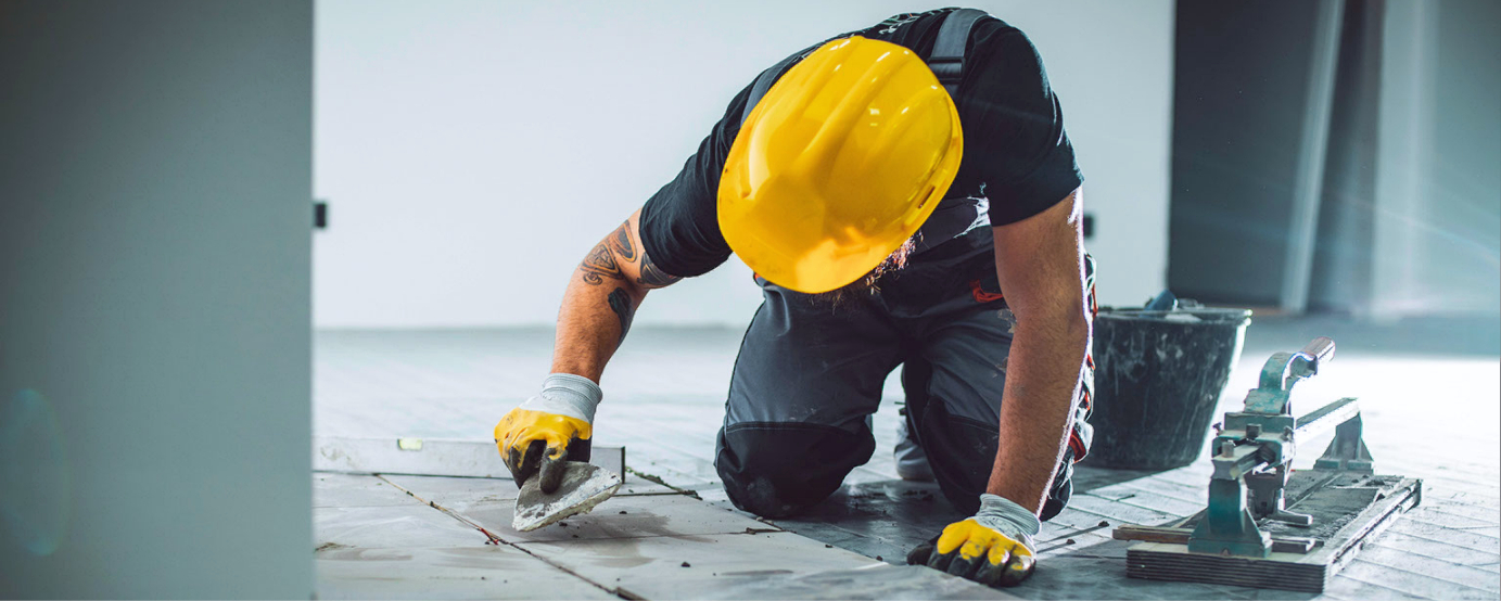 Contractor kneeling on floor preparing tile surface for install