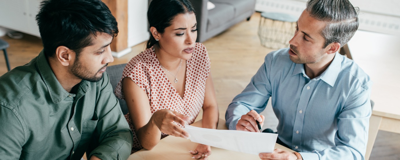 Man and woman and business professional sitting at a desk discussing a document
