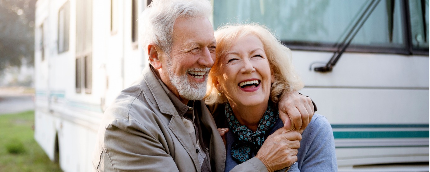 Smiling seniors a man and a woman standing in front of motor home