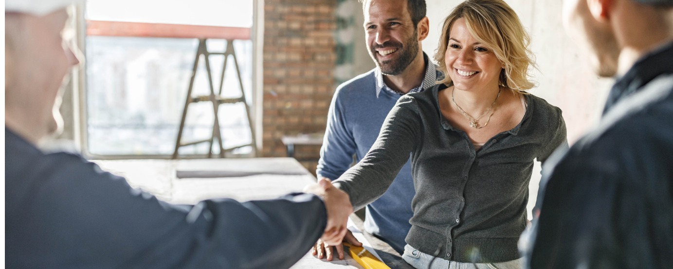Male and female customers shaking hands with businessman blurred ladder in background