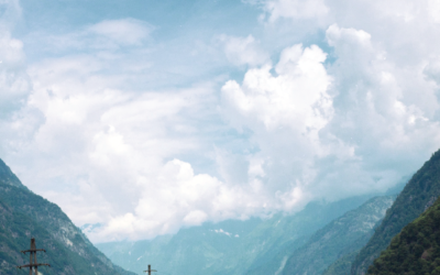 Photo of mountains surrounded by puffy white clouds.