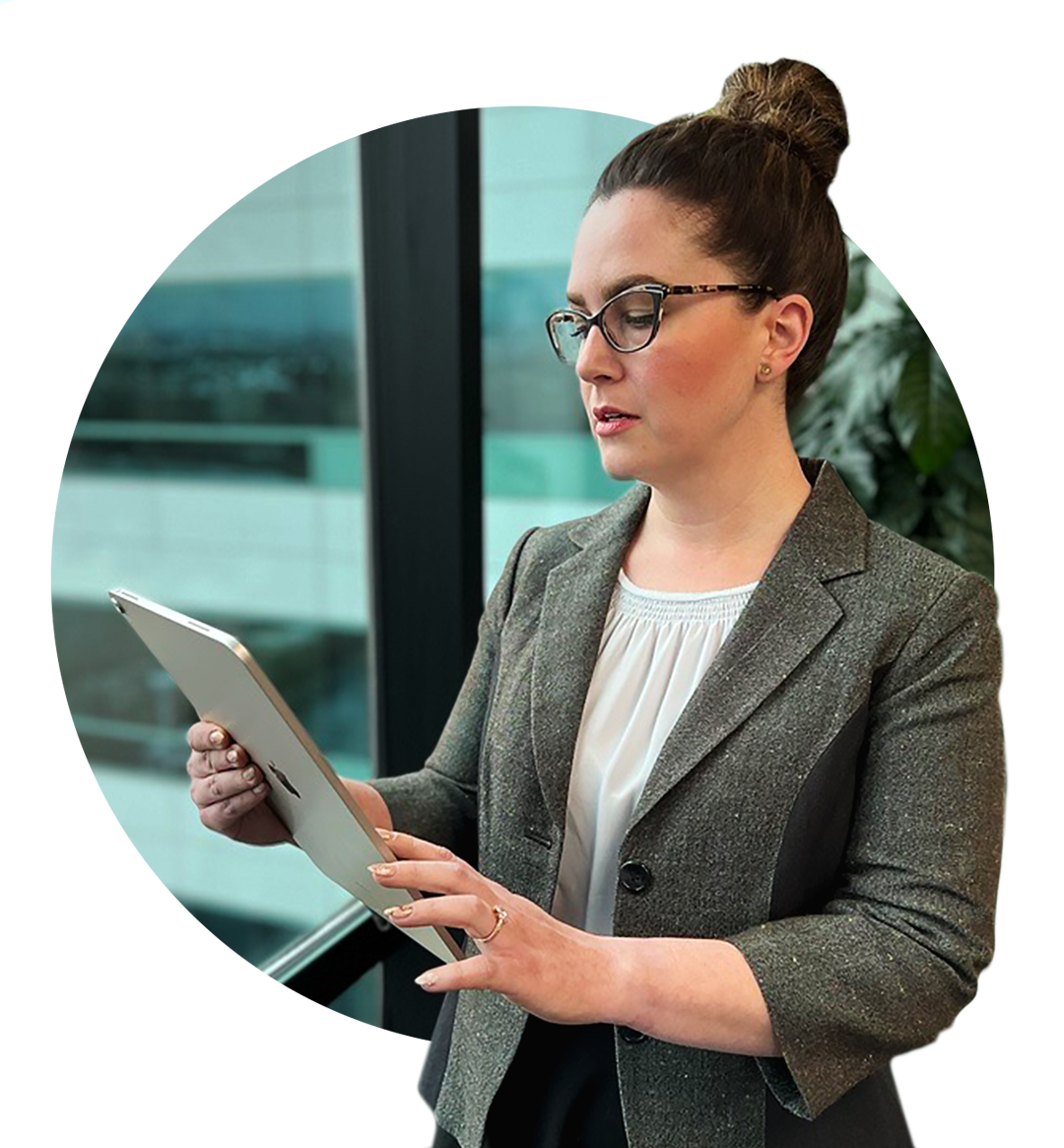 A female Bank employee stands looking at her iPad.