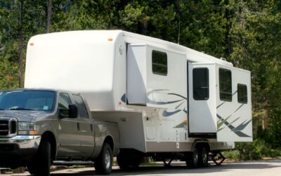 Picture of truck and RV with green trees in background.